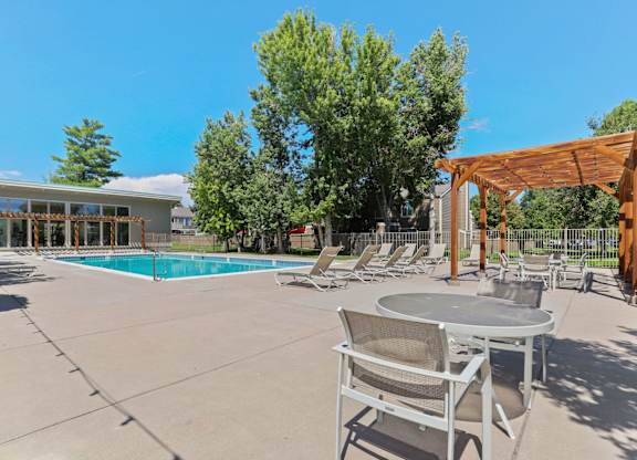 A poolside area with a table and chairs at The Ranch at Bear Creek Apartments, Lakewood, Colorado