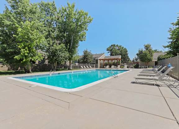 A large swimming pool surrounded by trees and lounge chairs at The Ranch at Bear Creek Apartments, Lakewood