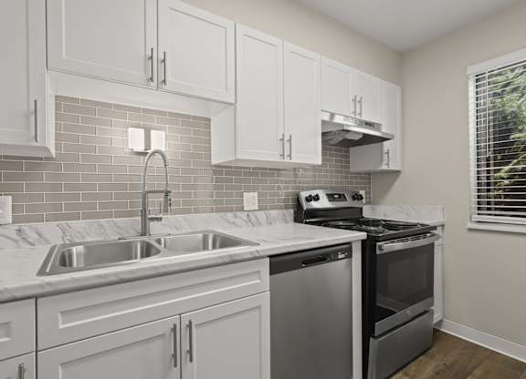 A kitchen with white cabinets and a stainless steel dishwasher at The Ranch at Bear Creek Apartments, Lakewood
