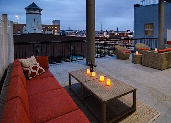 A balcony with a red couch and candles on a table.