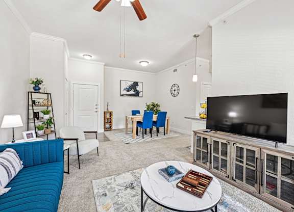 Living room with blue couch and television at The Laurel at Vintage Park 55+ Apartments, Tomball, 77377