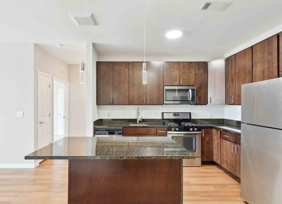 a kitchen with dark wood cabinets and an island with granite countertops at West 130, New York