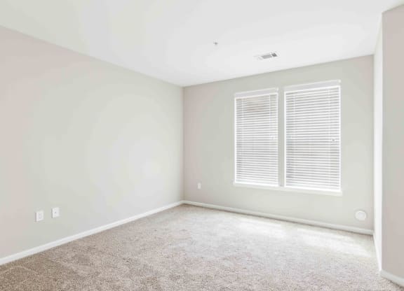 a bedroom with white walls and a window with white shutters at West 130, West Hempstead