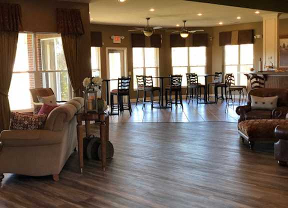 A living room with a couch, chairs, and a dining table. at The Legends at Steeplechase Apartments, Richwood