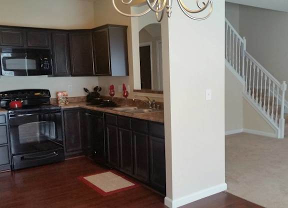 A kitchen with black cabinets and a white stove top oven. at The Legends at Steeplechase Apartments, Kentucky
