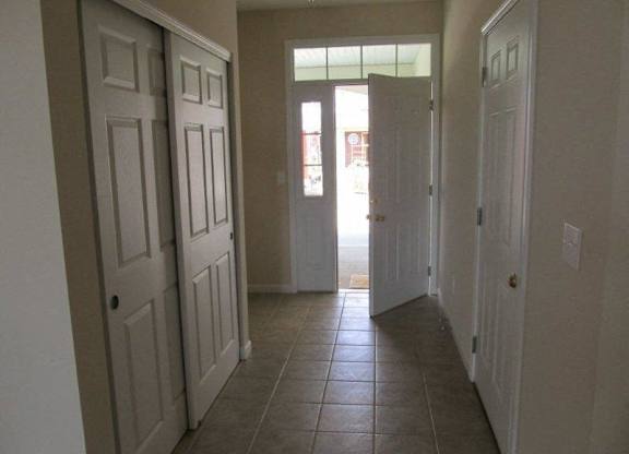 A hallway with white doors and brown tile flooring at The Legends at Steeplechase Apartments, Richwood