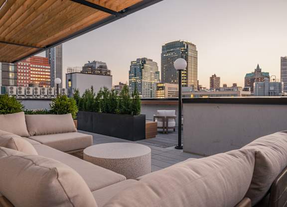 a living area with couches and a table on a balcony overlooking the city