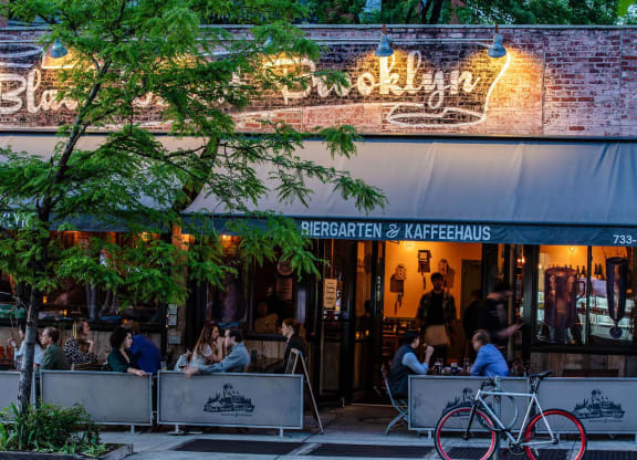 people sitting at tables outside of a restaurant at The Paxton, Brooklyn, 11201