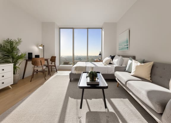 a living room with a couch and a table and a large window at The Paxton, Brooklyn, 11201
