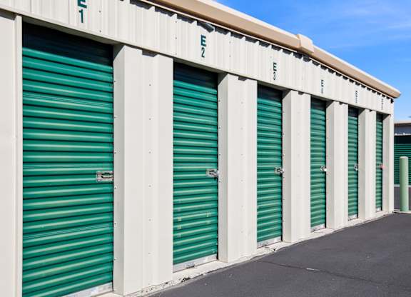 A series of storage units with green doors and white walls.