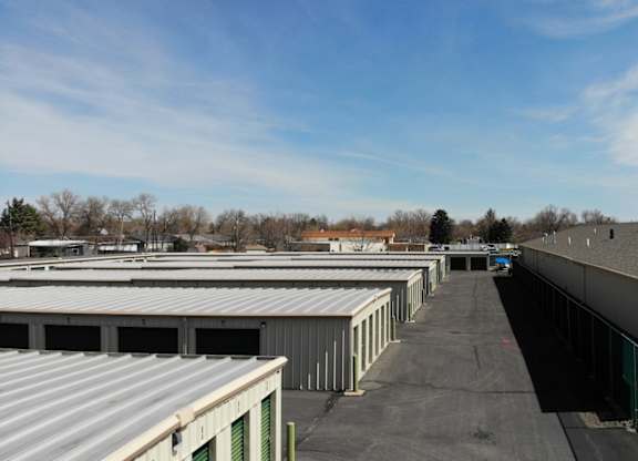 A parking lot with a green fence and a building on the right.