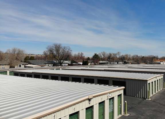 A row of storage units with green doors and a blue sky in the background.