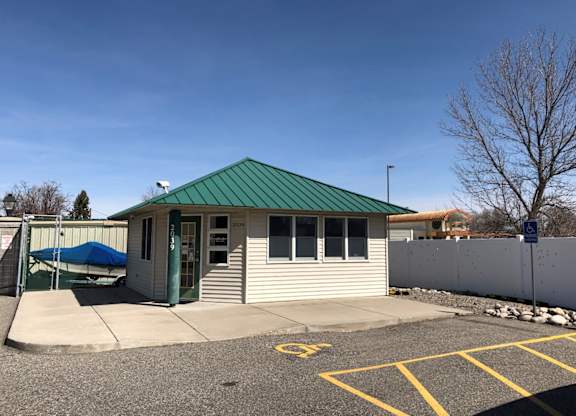 A small building with a green roof is surrounded by a parking lot.