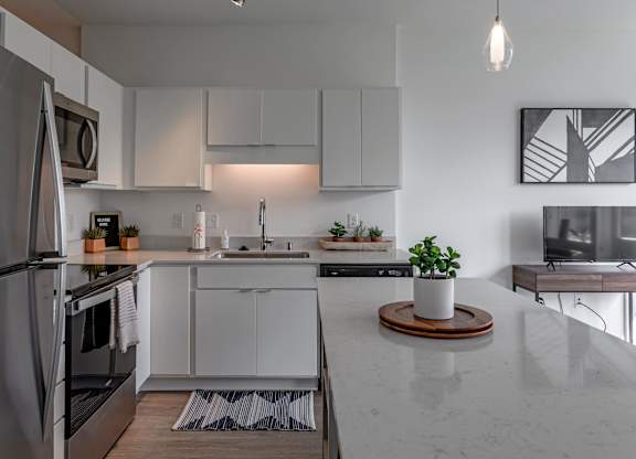 a kitchen with white cabinets and a marble counter top