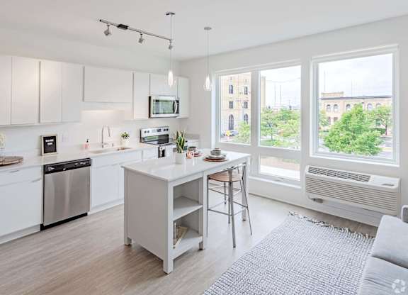 a white kitchen with an island and a large window