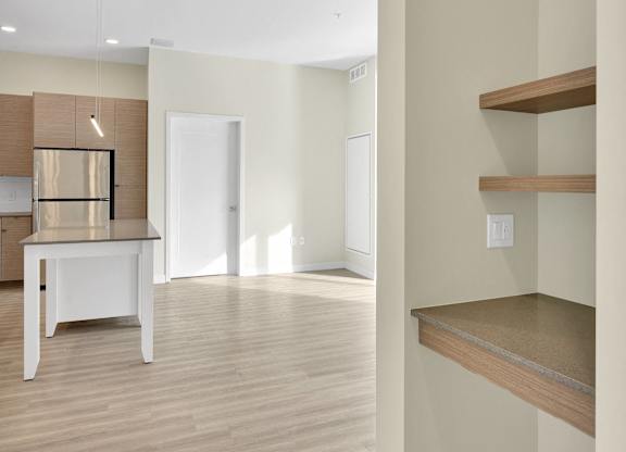 A kitchen with a white table and wooden shelves.