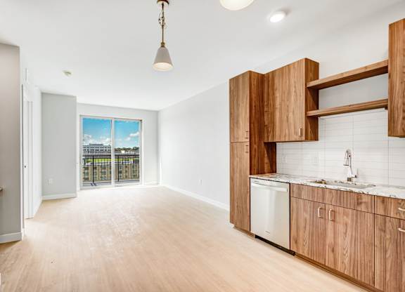 an empty room with a kitchen and a door to a balcony
