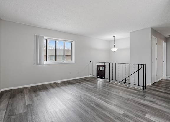an empty living room with hardwood floors and a window