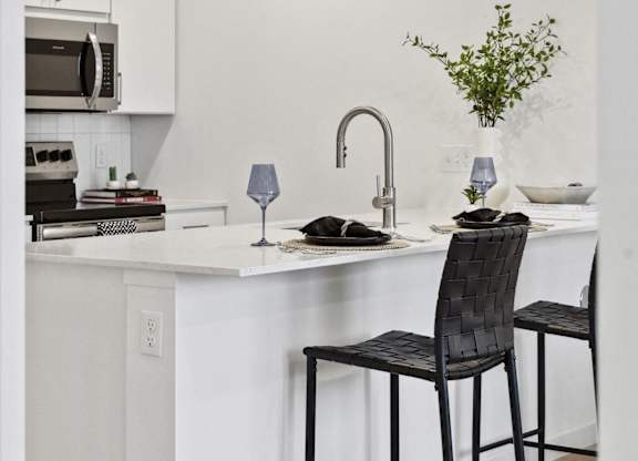 A kitchen with a white counter and a black chair.