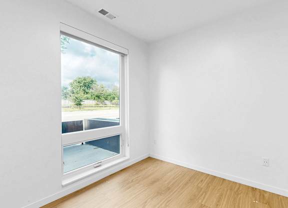 A room with a window overlooking a parking lot.