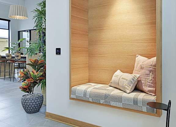 A modern room with a wooden panelled wall and a bench with cushions.