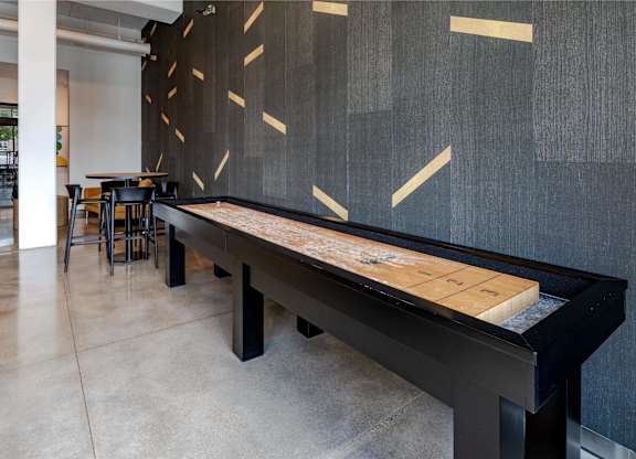 a shuffleboard table in a room with tables and chairs