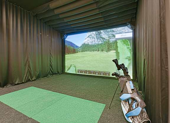 A golf simulator room with a screen showing a golf course.