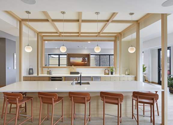 A kitchen with a white counter and brown stools.