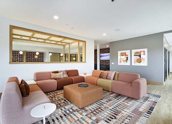 A living room with a pink couch, a white table, and a large mirror on the wall.