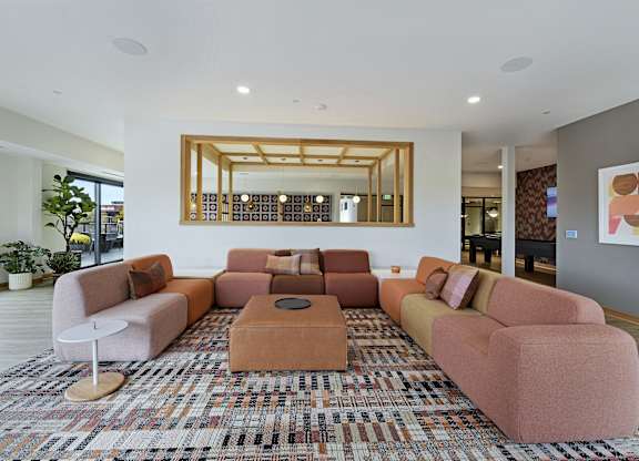 A living room with a large rug and a mirror on the wall.