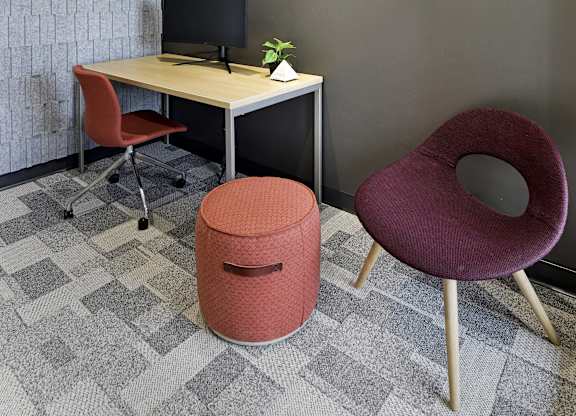A red chair sits in front of a desk with a computer monitor and keyboard.