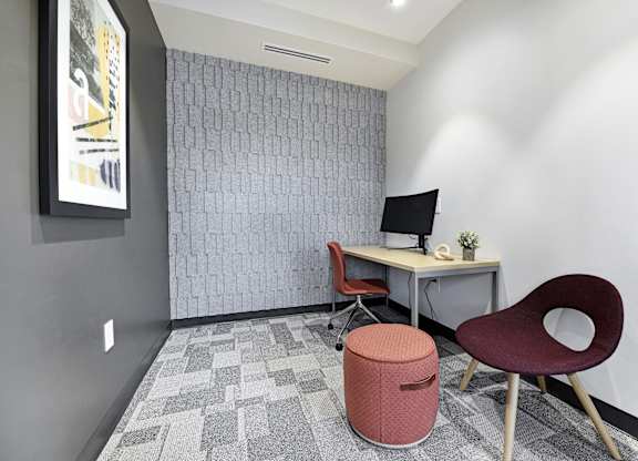 A room with a desk, chair, and a trash can.