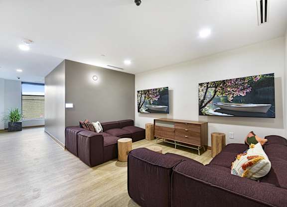A living room with a brown couch and a painting on the wall.