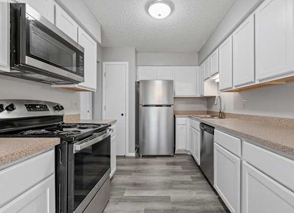 an empty kitchen with white cabinets and stainless steel appliances