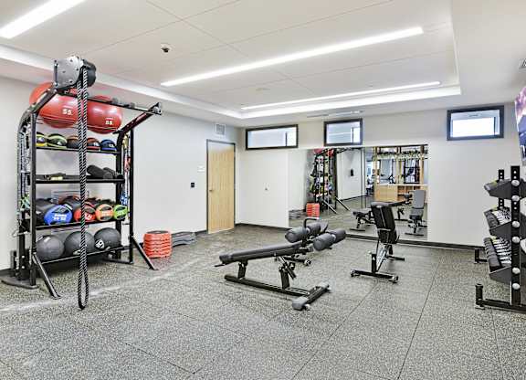 A gym with a variety of equipment including weights and benches.