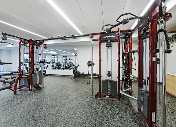 A gym with a variety of equipment including a weight bench and a leg press machine.