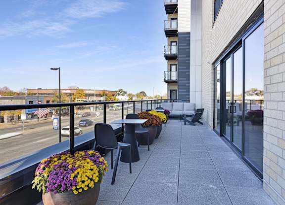 A balcony with a table and chairs overlooking a street.