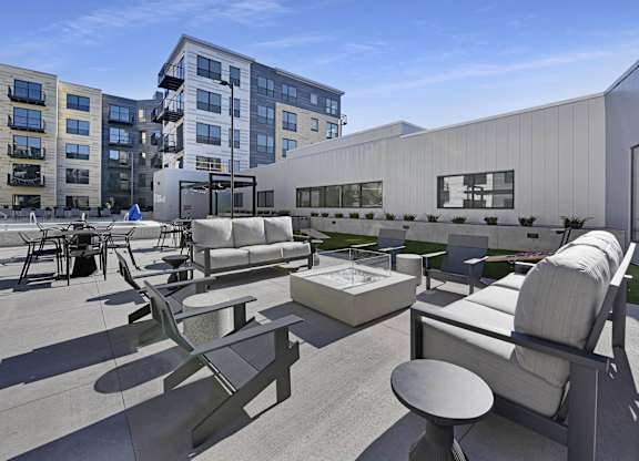 A modern outdoor seating area with concrete furniture and a white building in the background.