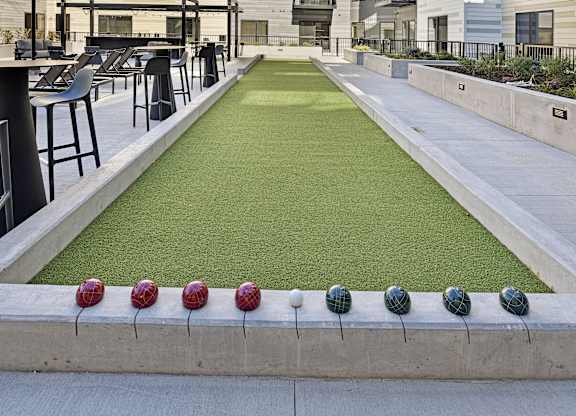 A miniature golf course is located in the courtyard of a modern apartment complex.