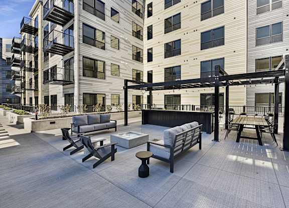 A patio area with a table and chairs is surrounded by apartment buildings.