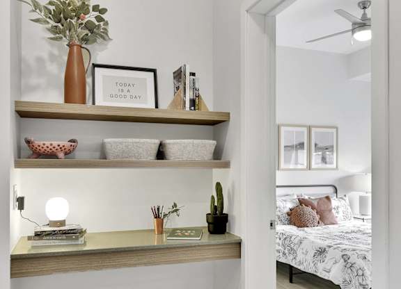 A bedroom with a bed, a shelf with decorative items, and a mirror.