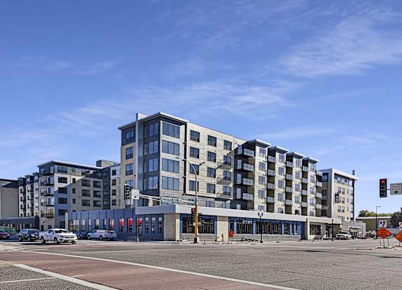 A modern multi-story building with a parking lot in front.