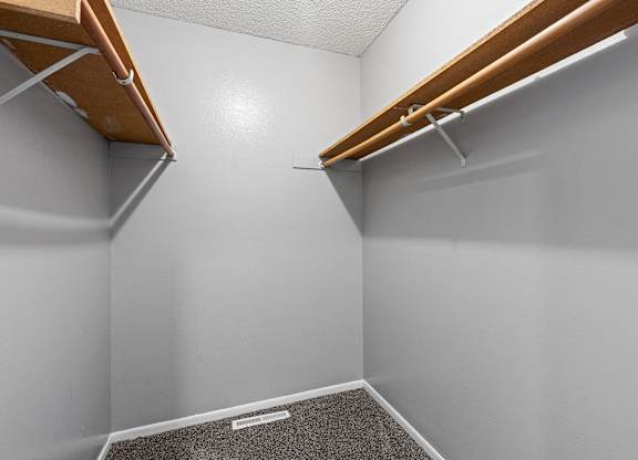 a walk in closet in a home with white walls and wood trim