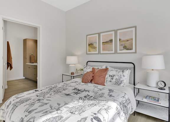 A bedroom with a large bed and a nightstand with a lamp on it.