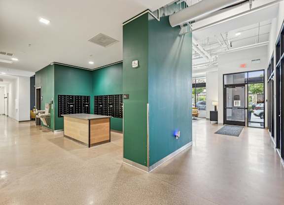 A long hallway with a green wall and a wooden bench.