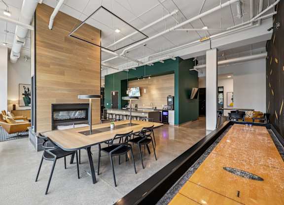 A room with a long table and chairs, a fireplace, and a bowling alley.