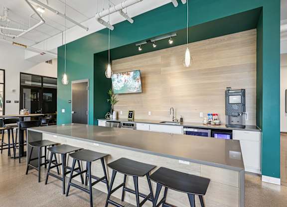 A modern kitchen with a long counter and bar stools.