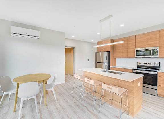 A modern kitchen with a wooden table and white chairs.