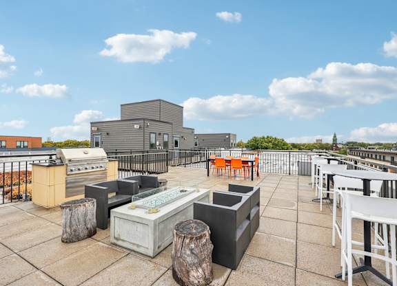 A rooftop patio with white chairs and a bar area.