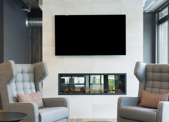 a living room with two chairs and a television on the wall